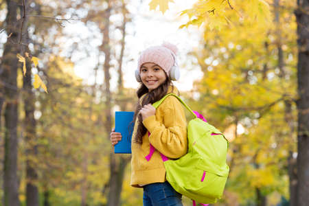 kid listen music in autumn park. fall is a time for study. back to school. concept of online...