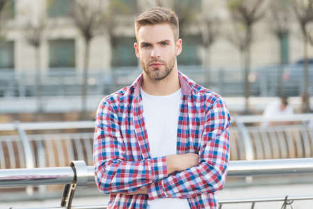 handsome man with crossed hands wearing casual checkered shirt outdoor and has stylish hairstyle, male fashion and barbershopの写真素材