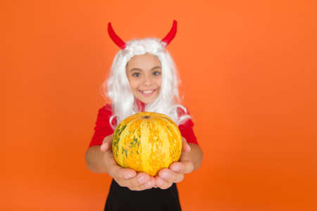 happy teenage girl with long wig hair wear devil horns hold pumpkin vegetable for autumn halloween...