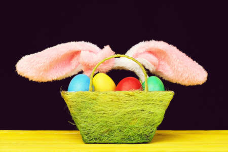 Easter bunny ears and basket filled with painted easter eggs