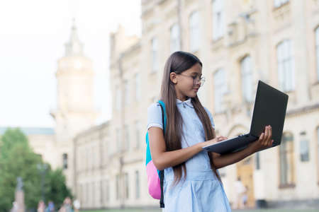 intelligent teen girl work on laptop online in school yard, education and childhood developmentの写真素材