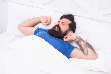 handsome mature male hipster in the morning yawning and stretching in bed, full of energyの写真素材