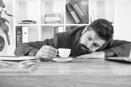 Hard morning. Bearded hipster formal suit relaxing with coffee. Office life. First coffee. Sleepless night. Procrastination is thief of time. Man handsome boss sleep in office drinking coffeeの写真素材