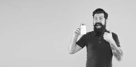 Male beauty product in jar. brutal bearded man hold vitamin. medicine pills and drugs. bio vitamin complex. happy hipster. healthy lifestyle and people concept. Food Supplements. copy spaceの写真素材
