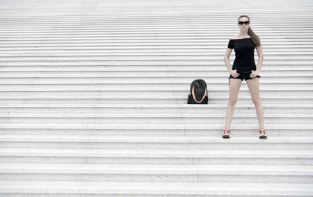 Girl tourist stand stony stairs near her backpack. Ready to explore new city. Woman sunglasses stylish black outfit walking paris. Vacation and travel concept. Touristic guide sightseeing excursionの写真素材