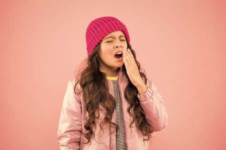 Sneezing. Cold climate weather. Little girl sick ill pink background. Kid puffer jacket and knitted hat. Winter cold flu. Health care. Feeling bad. Medical treatment. Flu remedies. Flu seasonの写真素材