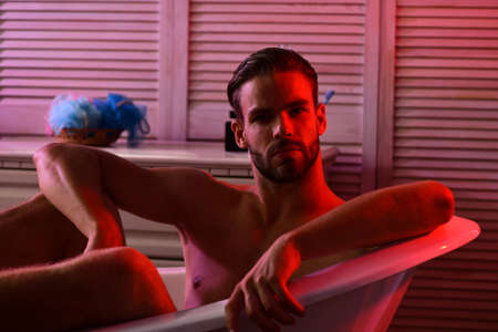 macho sitting in red lit bathroomの写真素材