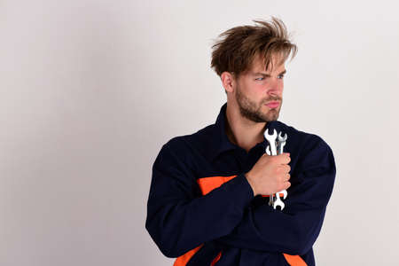 Man with serious face in uniform holds wrench tools