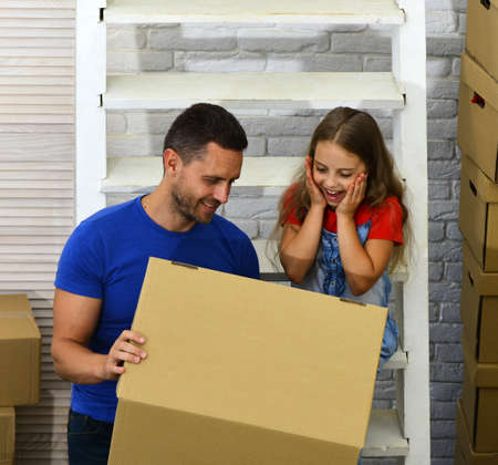 Father and child with excited faces look into box.