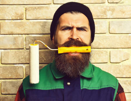 bearded painter man holding roller paint with serious faceの写真素材