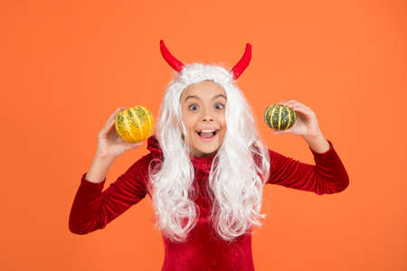 happy girl wear devil horns having long white hair wig holding halloween pumpkin, happy halloween traditionの写真素材