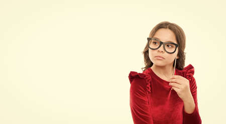 Smart baby. Kid hold cute eyeglasses photo booth props accessory. Child charming isolated white background. Girl hold eyeglasses for party. Child with eyeglasses copy space. Little nerd conceptの写真素材