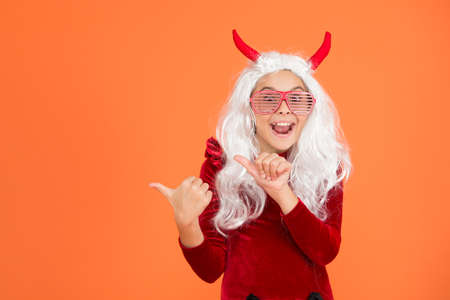 happy halloween devil girl. teenage child in imp horns. cheerful kid with white hair in fanny...