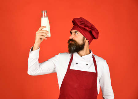 Cook with curious face in burgundy uniform holds milk.の写真素材