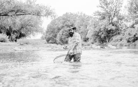 Bearded fisher catching trout fish with net. Fishing provides that connection with whole living world. Find peace of mind. Fishing is astonishing accessible recreational outdoor sport. Fishing hobbyの写真素材
