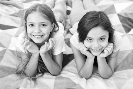 Comfortable relax. Small girls lay on bed. Our room. Spending time with friends. Small girls in bed. Happy children. Small children in bedroom. Kids relax. Smiling happy faces. Time to relaxの写真素材