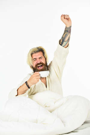 Man with beard in dressing gown. Guy in bath clothes hold coffee. Morning rituals concept. Tired man...