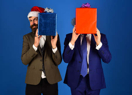 Businessmen hide faces behind red and blue present boxes.の写真素材