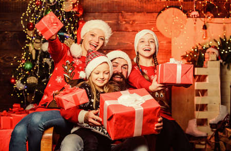 Christmas joy. Happy holidays. Parents and children opening christmas gifts. Father Santa claus and mother little daughters christmas tree background. Christmas tradition. Family bonding activitiesの写真素材