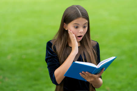 Surprise helps to study new things. Surprised child read study book outdoors. Knowledge and information. School library. Reading education. Motivation and interest. Attracting learners attentionの写真素材