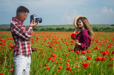 Amazing sunset in the poppy field for loving couple making photo on camera, nature beauty