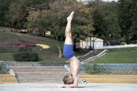 Athletic man doing yoga asanas in the parkの写真素材