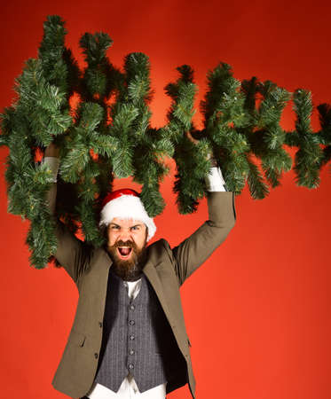Man in smart suit and Santa hat on red background.の写真素材