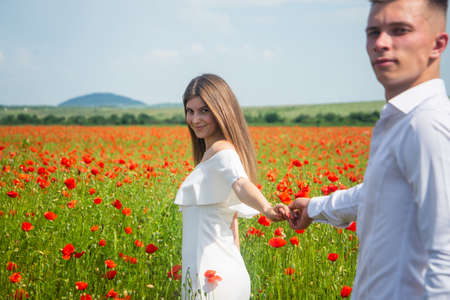 Happy couple in love walking in beautiful field of poppy flower on romantic day, loveの写真素材
