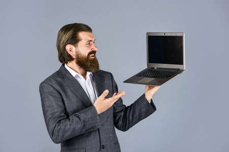 presenting product. happy caucasian bearded hipster with computer. male employee holding finance...