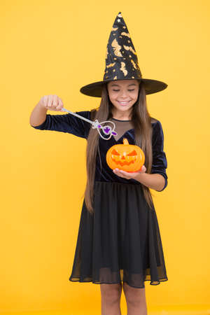 halloween teen girl in witch hat hold magic wand and pumpkin jack o lantern for witchcraft, happy halloweenの写真素材