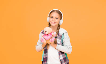 person that cares. hipster girl lpove play with toy. schoolgirl casual style hold bear toy. autumn time for knowledge. child listen music headset. childhood education and development. audio bookの写真素材
