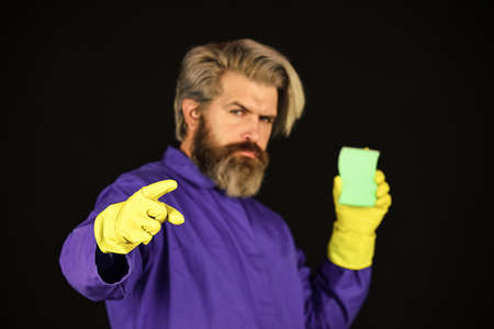 bearded man in yellow rubber gloves wiping dust using duster. cleaning at home. Housekeeping concept. Duty and cleaner. male using sponge. Take care hygiene. Bearded man with cleaning equipmentの写真素材