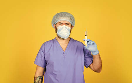 mature doctor use syringe in respirator mask. skilled nurse make injection. health worker dials vaccine in syringe. Physician or nurse giving vaccine against virusの写真素材