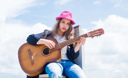 free music content. Teenage musician playing guitar. Portrait of little kid playing guitar on sky background. summer romantic playlist. Guitarist entertaining guests at party. small music loverの写真素材