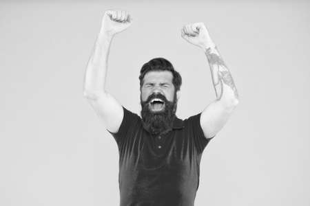 This is victory. Happy hipster with raised hands yellow background. Bearded man celebrate victory. Gambling and betting. Enjoying victory. Victory or success. Winner and championの写真素材