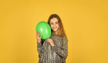 child wear sparkling dress yellow background. happy kid play with balloons. balloons for birthday party. colorful and bright surprise. childhood happiness. small girl hold party balloonの写真素材