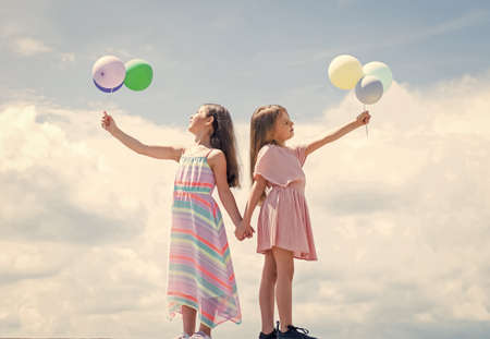 happy childhood. summer vacation. small girls embrace. love and support. concept of sisterhood and friendship. family bonding time. best friends with balloon. two sisters hold party balloonの写真素材