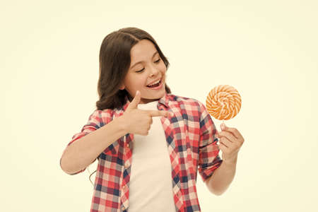 Look at this. Little girl point at candy isolated on white. Small child smile with hard candy on...