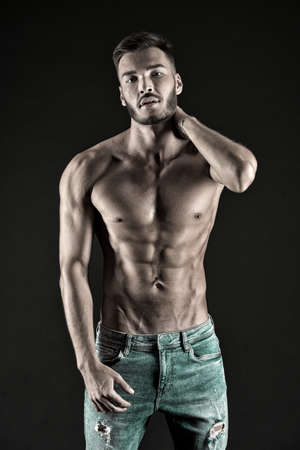 Check out my shape. Man muscular torso tense muscles veins denim pants. Macho muscular chest looks attractive black background. Athlete with muscular body on confident face proud of his shapeの写真素材
