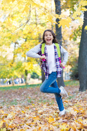 Energetic little kid carry backpack running to school in autumn park outdoors, September 1の写真素材