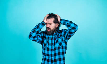 expressing human emotions. suffering man in checkered shirt. man with headache on blue background....