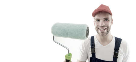 Renovation service. Paint and renovate. Decorator painting wall. Man smiling face in cap hold paint roller close up. Worker painter decorator concept. Decorator creative work. Professional occupationの写真素材