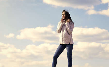 Freshness of wind. Woman fashion model outdoors. Woman enjoying cool weather. Matching style and class with luxury and comfort. Beauty and fashion look. Windy day. Girl jacket cloudy sky backgroundの写真素材