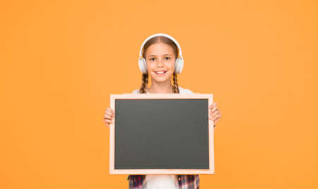 hipster girl hold empty blackboard. schoolgirl casual style show information. school mart shopping. music in her headphones. child presenting project. welcome to our modern school. Dream bigの写真素材