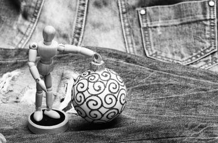 Christmas decorations concept. Christmas decorations on denim background close up. Wooden human body toy hold christmas decoration ball. Christmas decorative toys. Wooden model and ornamentsの写真素材