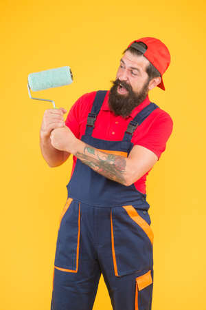 happy bearded man with paint roller. painter at painting works. hipster change wall color. repair and building. craftsman on construction. creativity. master of reconstructionの写真素材