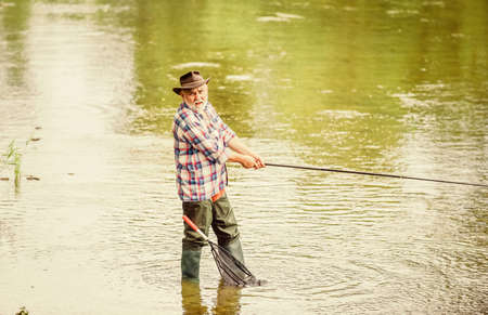 Retired fisherman. Male leisure. Fisherman with fishing rod. Activity and hobby. Fishing freshwater lake pond river. Happiness is rod in your hand. Senior man catching fish. Mature man fishingの写真素材