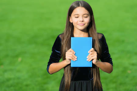 Learning by heart. Happy child learn from book with closed eyes. School library. Reading education....