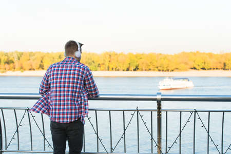 young handsome man in checkered shirt wear modern headphones listening music outdoor, copy space, relaxの写真素材