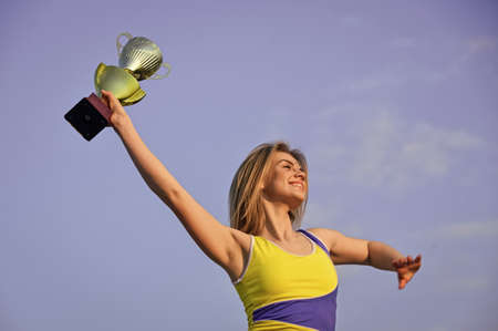 Conception of victory in the competition. happy woman with gold champion cup. successful prize winner. Feeling free and confident. Declaring the winner. girl celebrates victory in competitionの写真素材